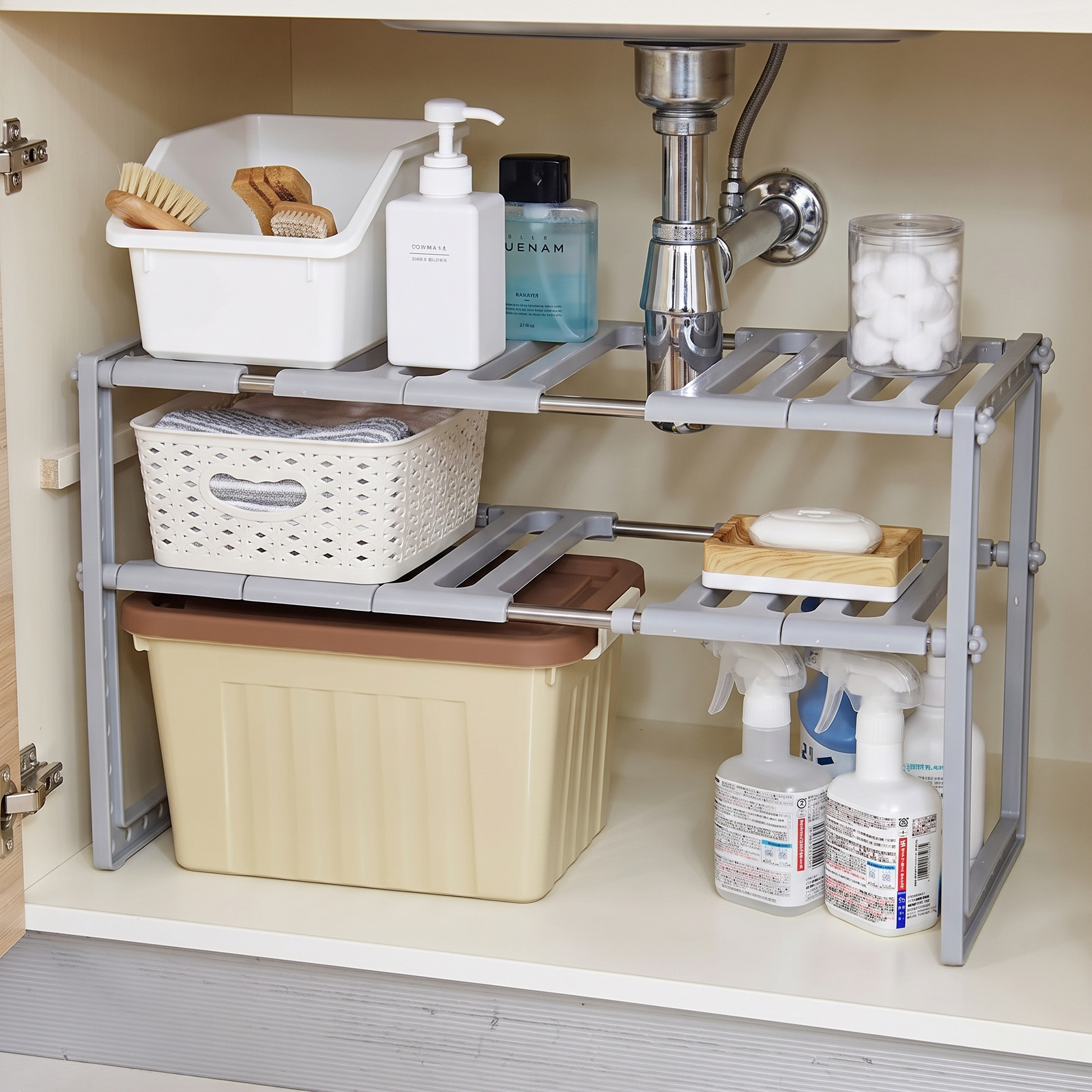 Expandable two-tier organizer fitted around plumbing beneath a sink