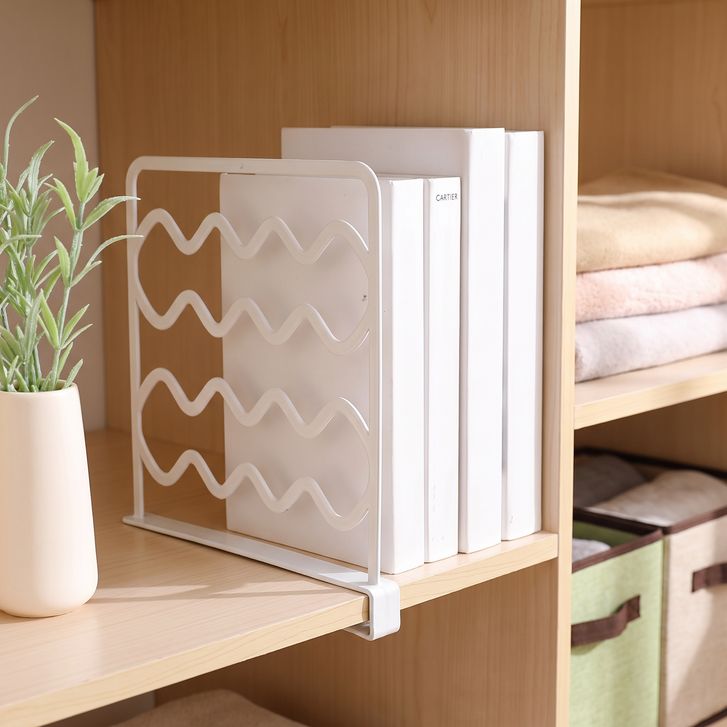 White shelf divider keeping books upright on a closet shelf